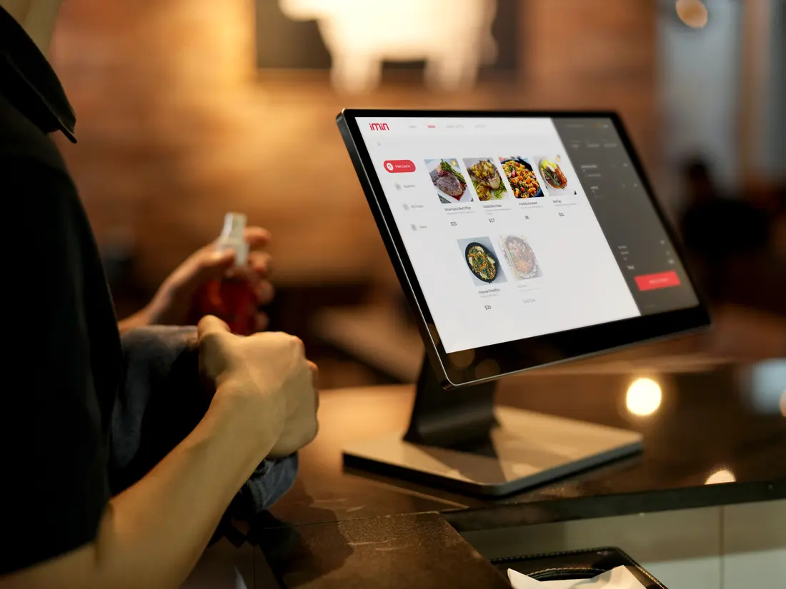 A point-of-sale terminal displaying a food menu on a café counter