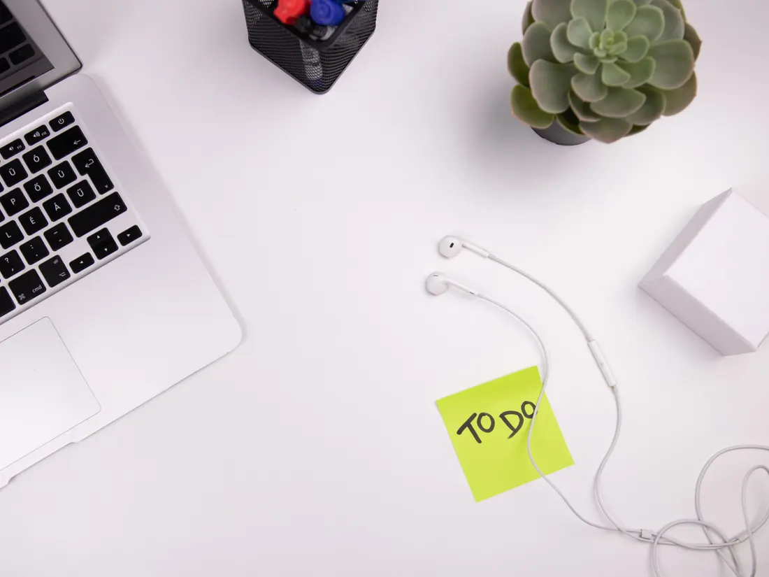 A laptop and a yellow sticky note reading "TO DO" on a clean white desk