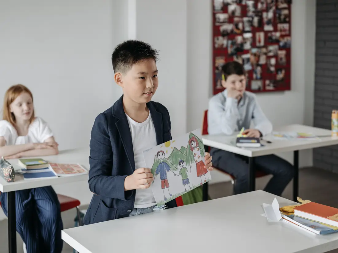 A pupil holding up their work at the front of a primary classroom